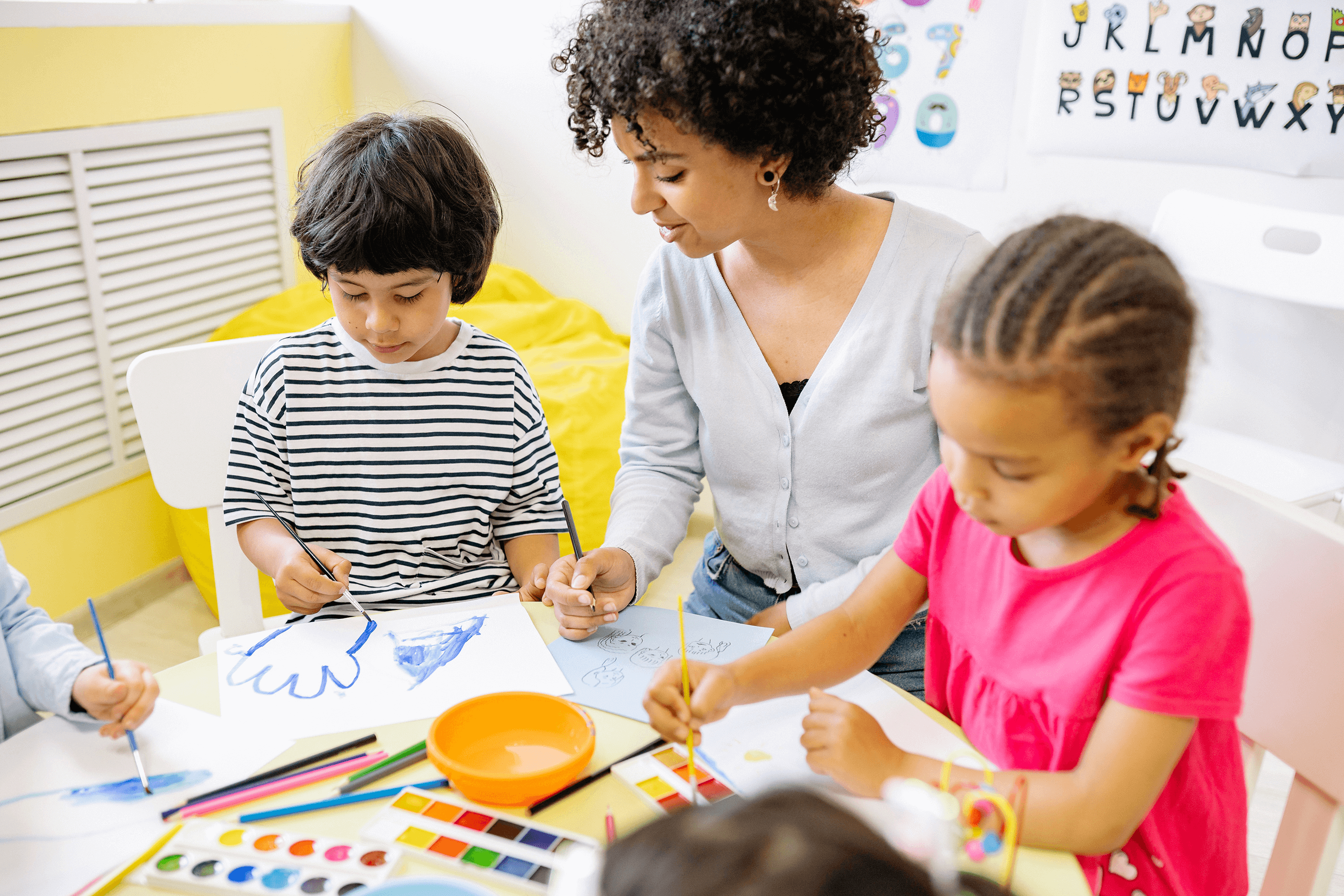 Woman working in behavioral health helping children with developmental needs paint